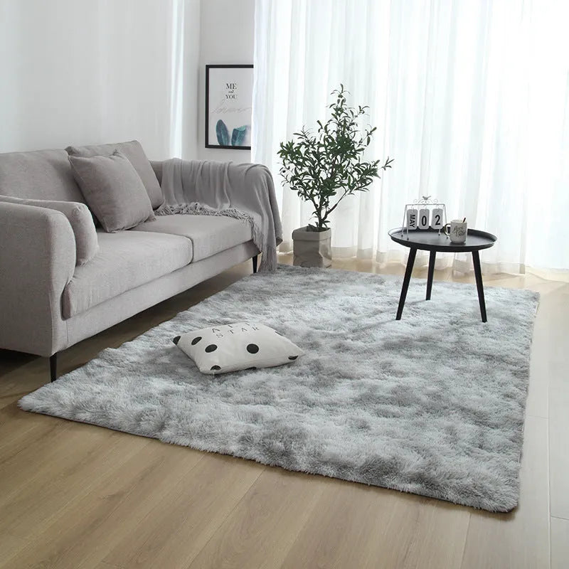 Soft fluffy plain rectangle carpet with anti-slip dots on backing, shown in a light grey colour on a wooden floor.