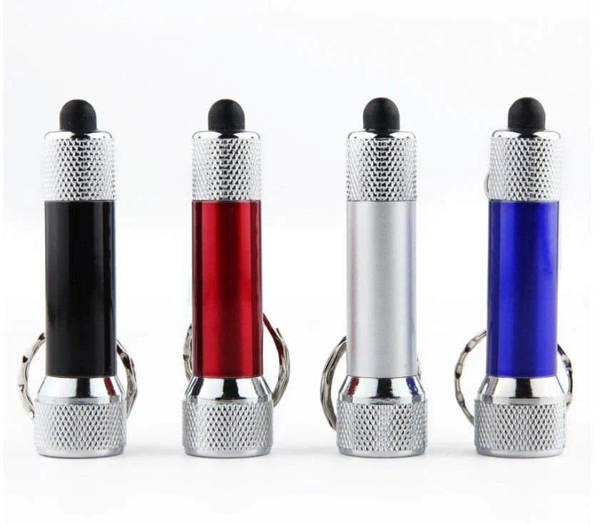 Compact aluminium LED keychain torch in four colours: white, black, red, and blue.