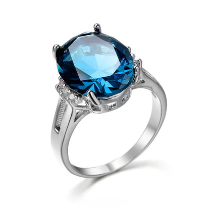Blue black geometric ellipse shaped copper ring with an electroplated finish on a hand.