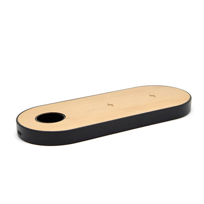 Ultra-thin bamboo and wood wireless charging stand for smartphones on a desk.