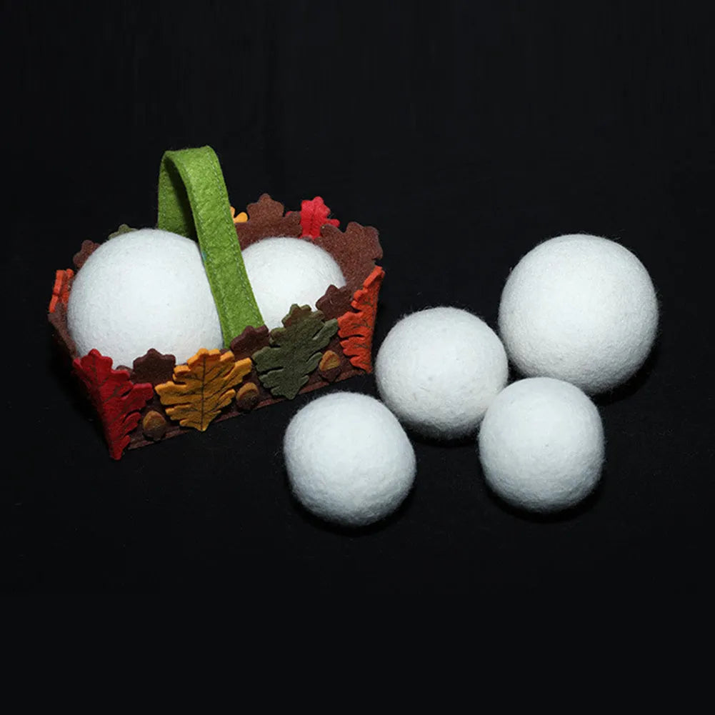 A 100% wool drying ball for laundry next to a plain cotton storage bag on a background.