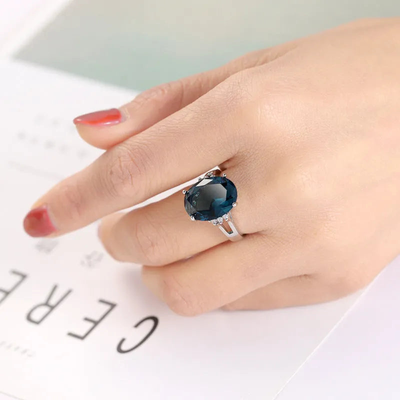 Blue black geometric ellipse shaped copper ring with an electroplated finish on a hand.