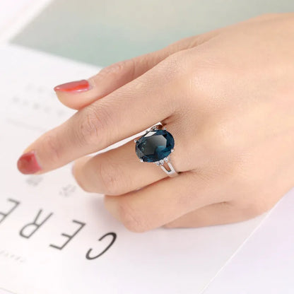 Blue black geometric ellipse shaped copper ring with an electroplated finish on a hand.