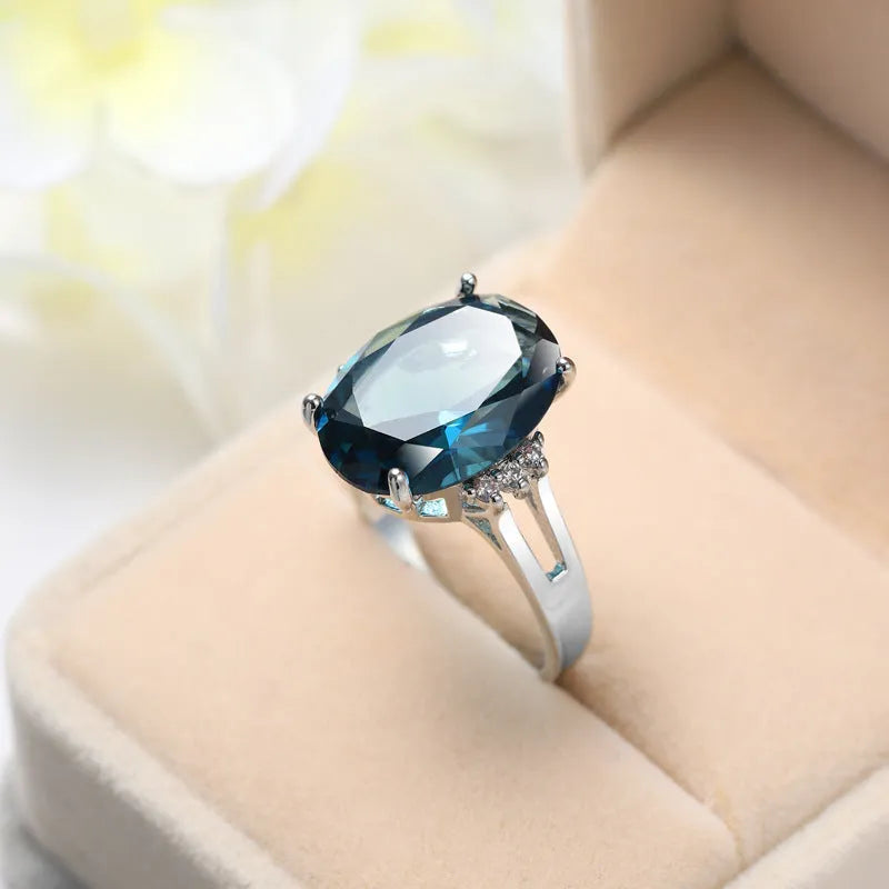 Blue black geometric ellipse shaped copper ring with an electroplated finish on a hand.