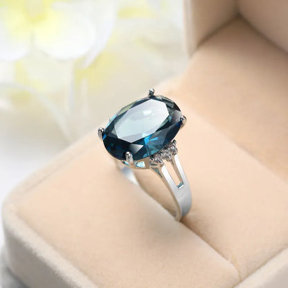 Blue black geometric ellipse shaped copper ring with an electroplated finish on a hand.