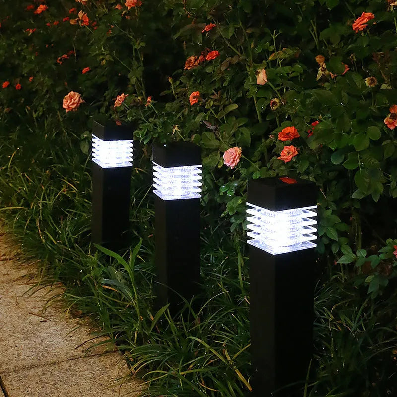 A tall, cuboid-shaped white solar lawn lamp standing in a garden.