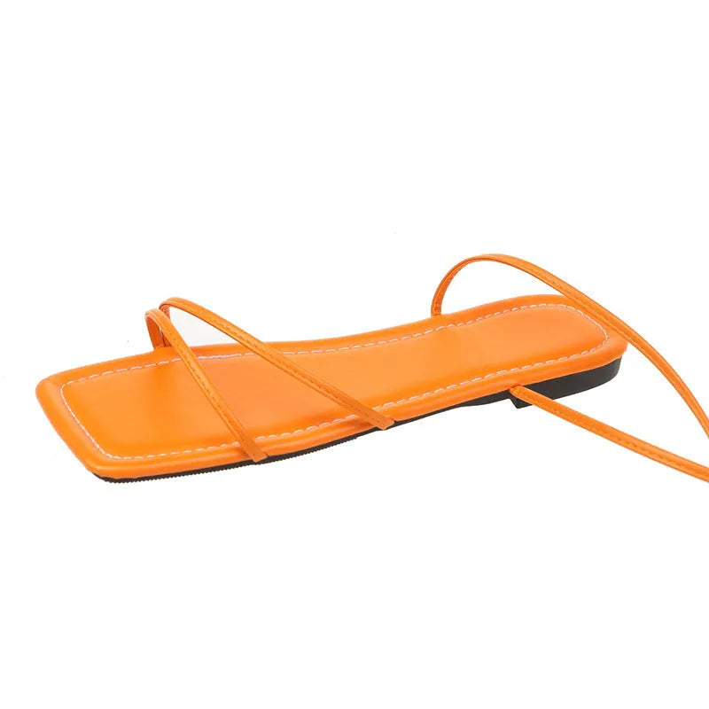 Women's white ankle-ring flat sandals with bandage cloth strap and front lace-up on a rubber sole.