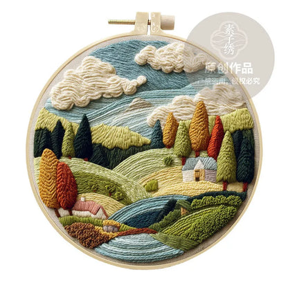 Complete DIY embroidery kit with 15cm bamboo frame, pre-printed landscape fabric, threads, and needles laid out.