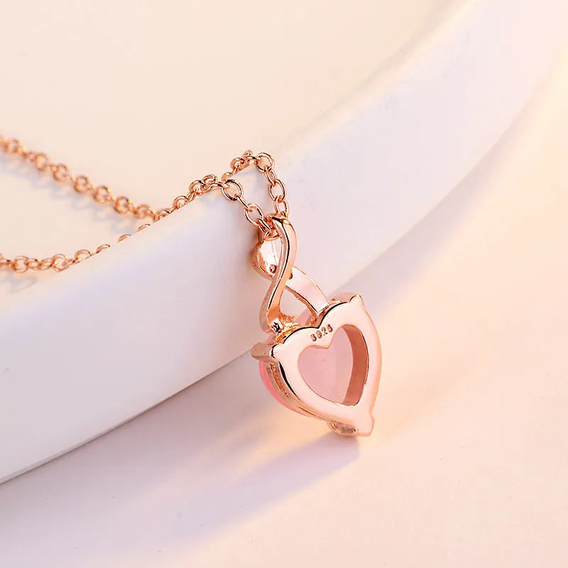 Women's heart-shaped pink crystal pendant necklace with rose gold electroplated cross chain for everyday wear or romantic occasions, featuring a synthetic crystal centrepiece set in copper alloy with heart-shaped love motif jewellery design