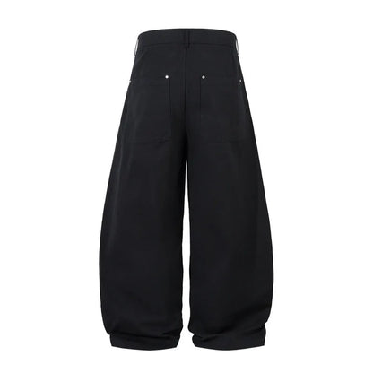 Men's black cotton pleated casual trousers with a loose-fitting wide-leg silhouette.