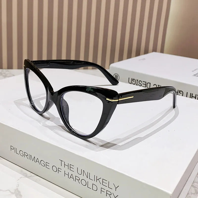 Women's black floral cat's eye reading glasses with large frames on a wooden table.