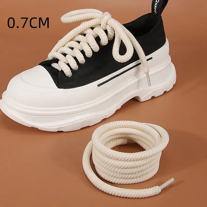Round woven white, beige, and black shoelaces for bread shoes showing different lengths on a flat surface.