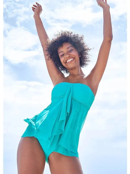 Woman wearing a strapless solid colour one-piece swimsuit or swim dress on the beach.