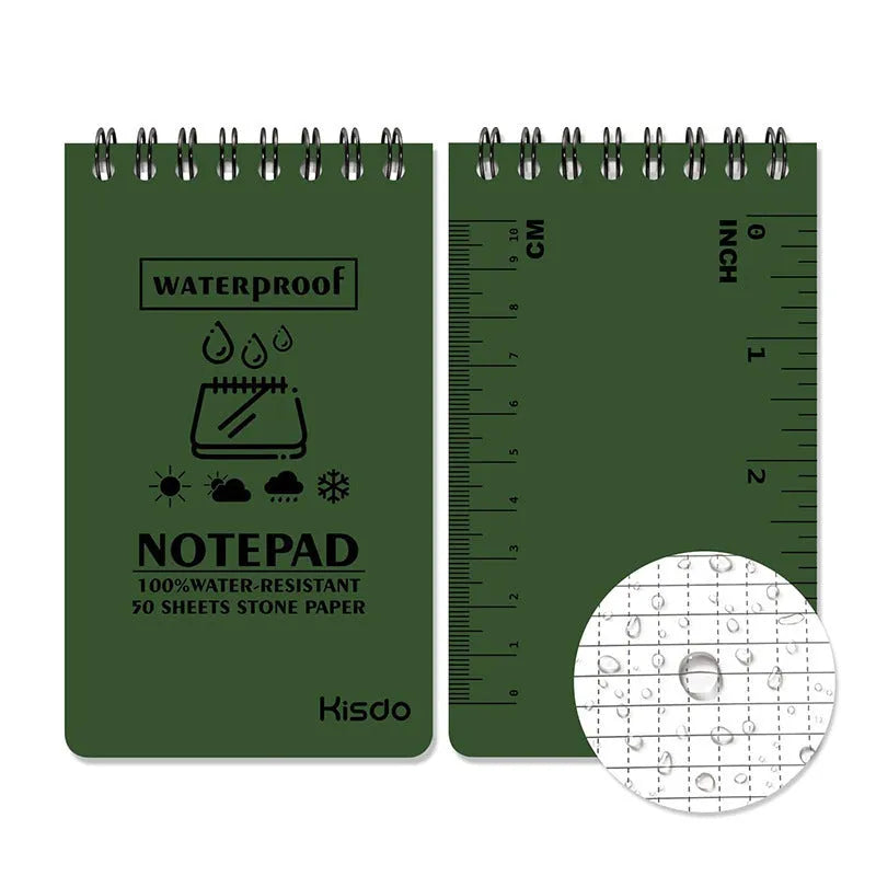 Spiral-bound waterproof notepad in camouflage colour, open on a wooden surface with a pen.
