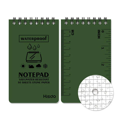 Spiral-bound waterproof notepad in camouflage colour, open on a wooden surface with a pen.