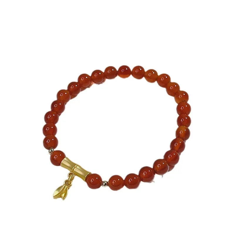Close-up of a red agate bracelet with a dragon charm and Lucky Bag symbol on a wrist.