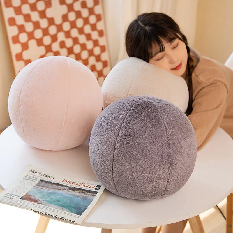 A soft, grey plush toy pillow with a round, furry design that adds a cosy and whimsical touch to home decor.