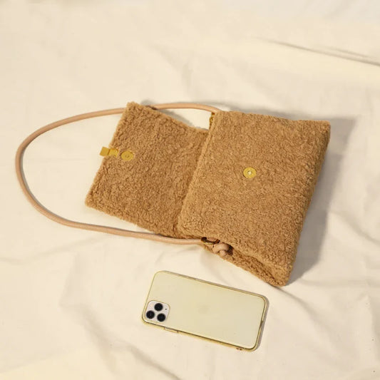 A stylish faux lamb wool crossbody bag in a neutral colour, featuring a double strap design and multiple interior compartments for organised storage.