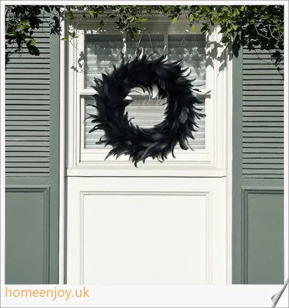 Black Halloween wreath made of luxurious natural feathers in shades of onyx, green, and purple
