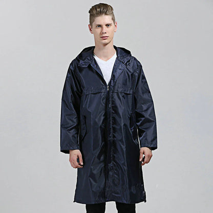 A man wearing a navy blue waterproof nylon raincoat standing in a field