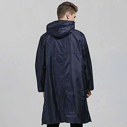 A man wearing a navy blue waterproof nylon raincoat standing in a field