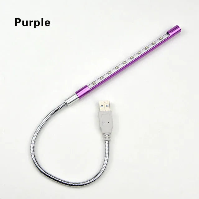 Spiral shaped silver aluminium USB LED desk lamp bent on a wooden desk.