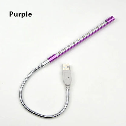 Spiral shaped silver aluminium USB LED desk lamp bent on a wooden desk.