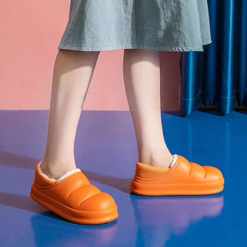 Pair of yellow waterproof EVA slippers with plush lining and a textured non-slip sole on a wooden floor.