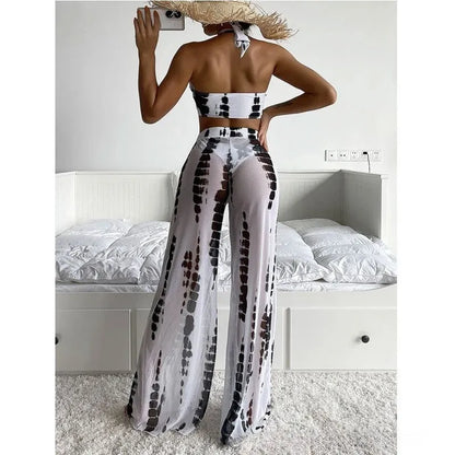 Women's black printed three-piece swimsuit set with mesh trousers laid flat.