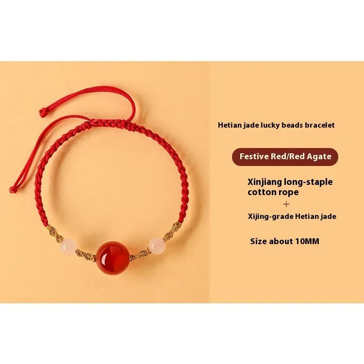 Hand-woven red rope bracelet with Hetian jade lucky beads on a wrist.