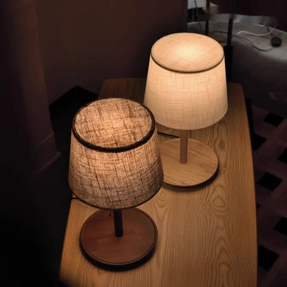 Walnut coloured solid wood bedside lamp with white fabric shade and cable switch.