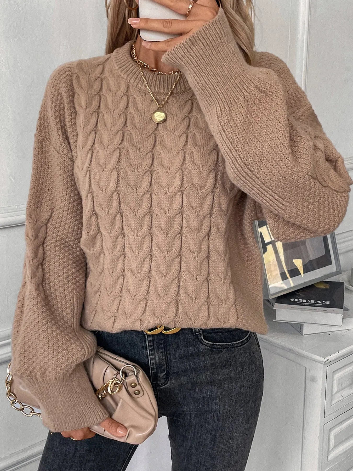Women's beige twist knit loose sweater with round neck and regular sleeves on a hanger
