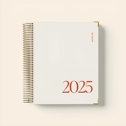 Cherry red A5 daily schedule coil notebook with spiral binding lying open.