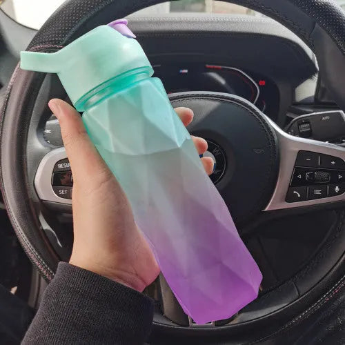 White spray water bottle with black leakproof lid and handle strap on a table