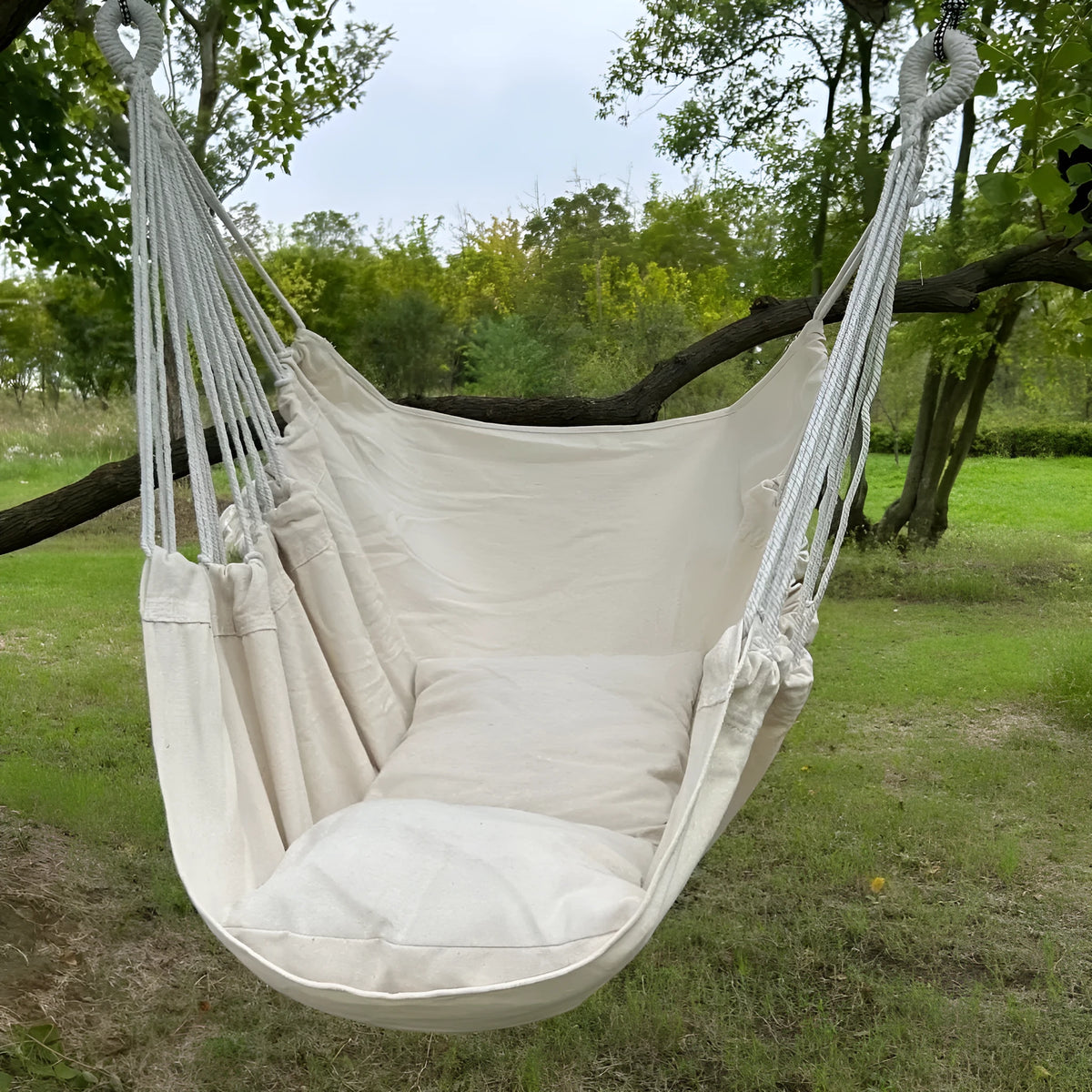 Folding outdoor tassel hammock in beige with canvas seat, cushion, and three-section iron pipe
