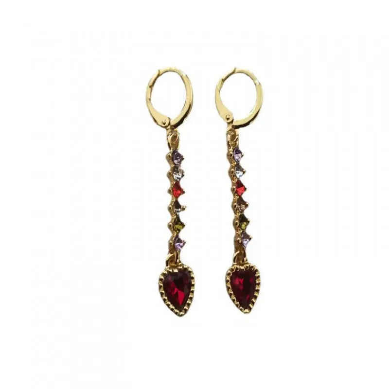A pair of small gold-coloured heart-shaped alloy earrings on a plain background.