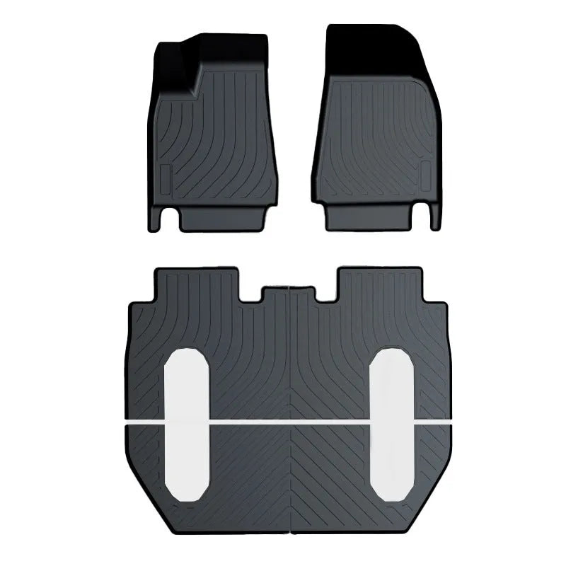 Custom black rubber floor mats fitted in a Tesla Model 3, showing deep grooves and raised edges.