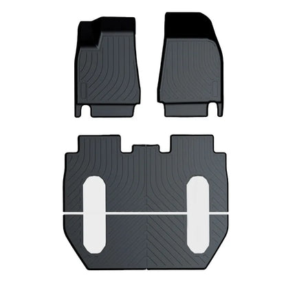 Custom black rubber floor mats fitted in a Tesla Model 3, showing deep grooves and raised edges.
