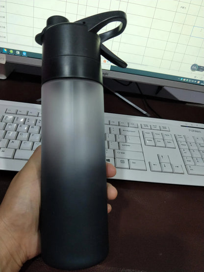 White spray water bottle with black leakproof lid and handle strap on a table