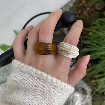 Geometric Chinese-style wide resin ring in brown and white colours on a plain background.