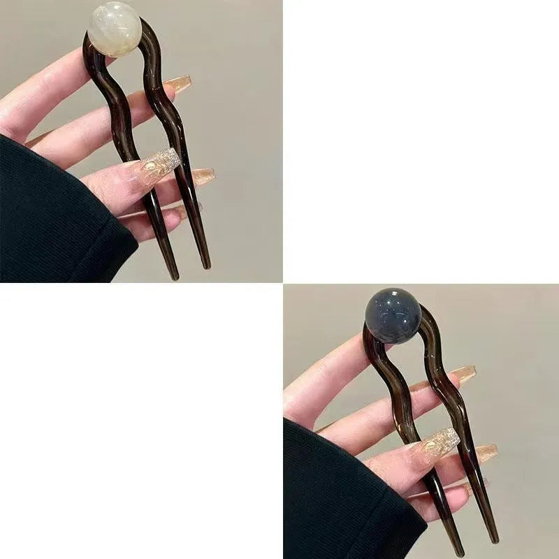 A set of U-shaped acrylic hair barrettes with a simple ball decoration in beige, caramel, and dark grey colours.