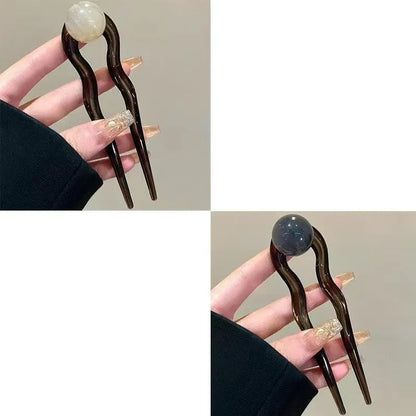 A set of U-shaped acrylic hair barrettes with a simple ball decoration in beige, caramel, and dark grey colours.
