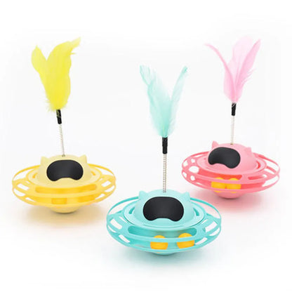 Pink self-hi tumbler cat toy with plush element on a turntable base, next to a play stick.
