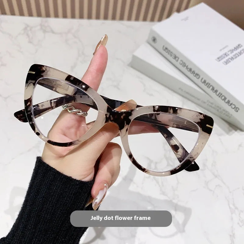 Women's black floral cat's eye reading glasses with large frames on a wooden table.