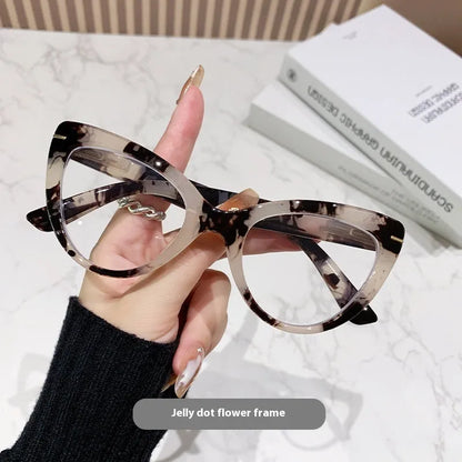 Women's black floral cat's eye reading glasses with large frames on a wooden table.