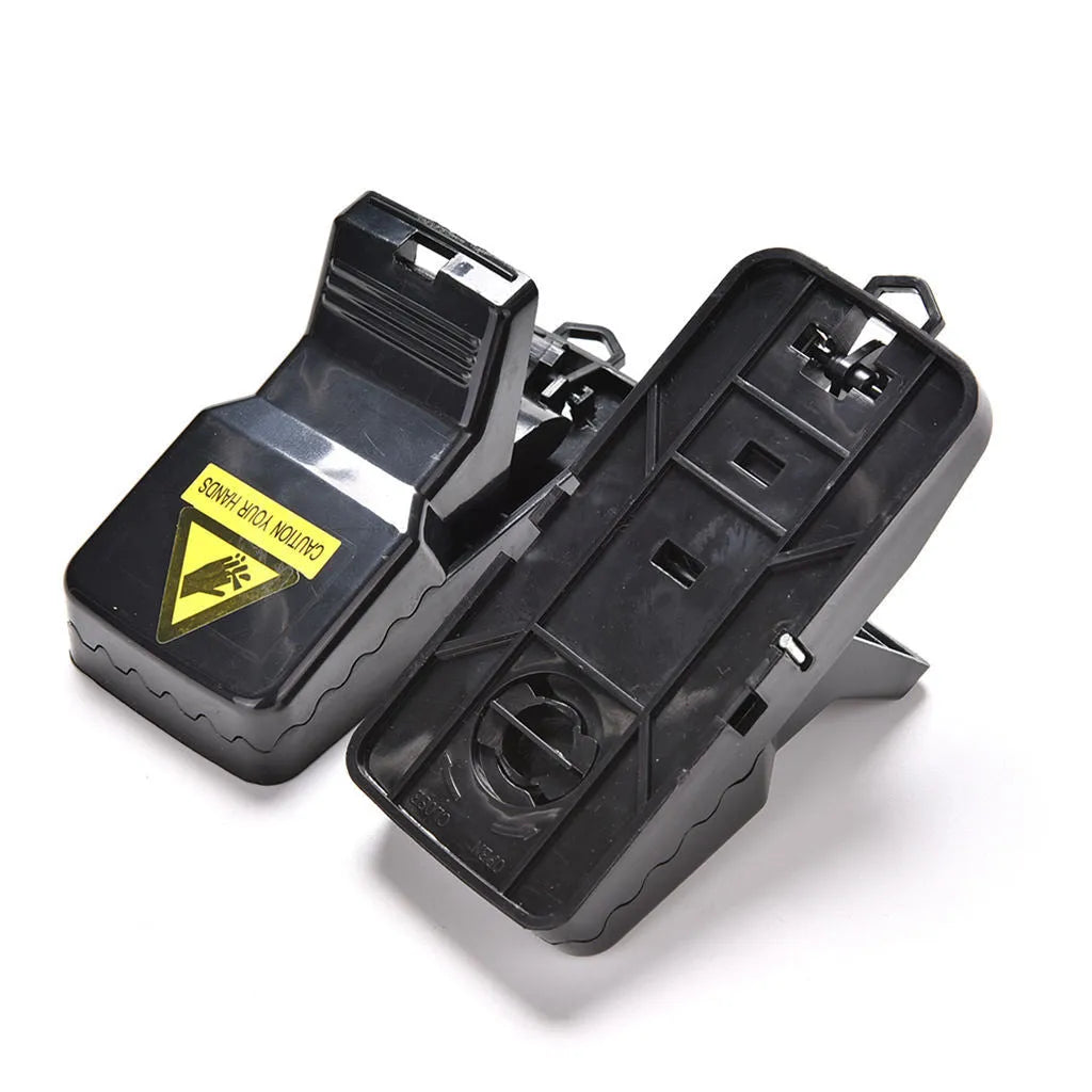 Six black plastic snapping mousetraps laid out on a surface, showing their size and smooth construction.