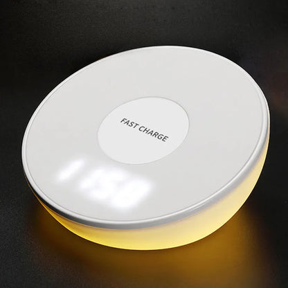 White wireless charging pad with digital clock display and three control buttons on a bedside table.