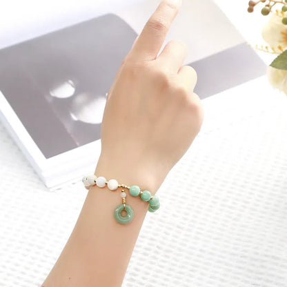 Blue Burma jade bead bracelet with copper horseshoe screw safety buckle on a wrist.