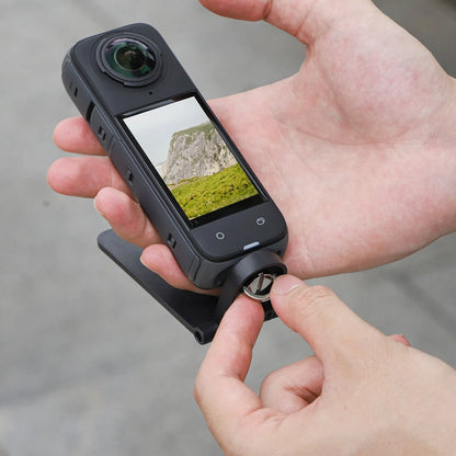 Black magnetic bracket base and handle accessory for an Insta360 X4 camera on a desktop.