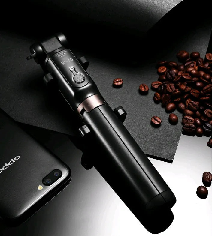 Aluminium tripod selfie stick with extended phone clip and Bluetooth remote on a table